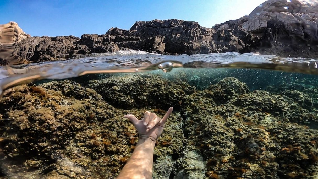 Ma extesa sobre un fons d'aigua cristalina i un fons rocós al Cap de Creus.